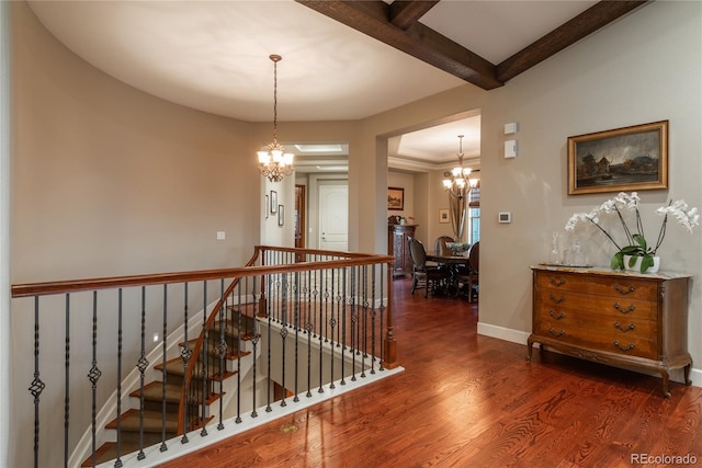 corridor with wood finished floors, baseboards, beam ceiling, an upstairs landing, and a chandelier