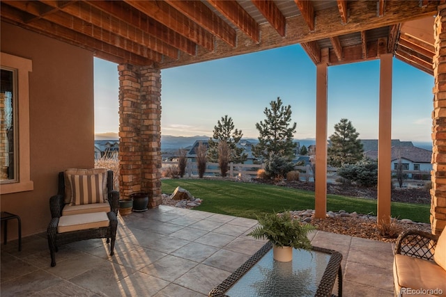 patio terrace at dusk featuring a yard