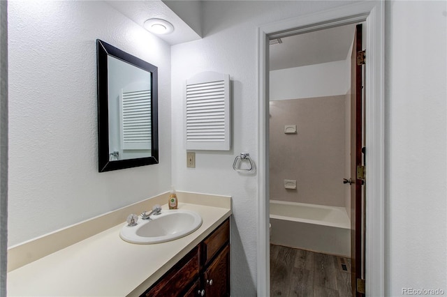 bathroom featuring hardwood / wood-style flooring, vanity, and tub / shower combination