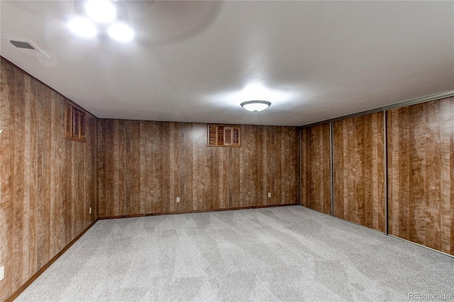 interior space with light colored carpet and wood walls