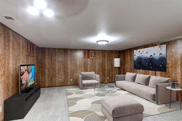 living room featuring wooden walls, visible vents, and light colored carpet