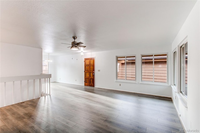 unfurnished room with a textured ceiling, ceiling fan with notable chandelier, and wood finished floors