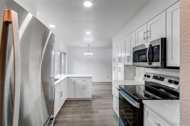 kitchen featuring a peninsula, appliances with stainless steel finishes, white cabinets, and wood finished floors