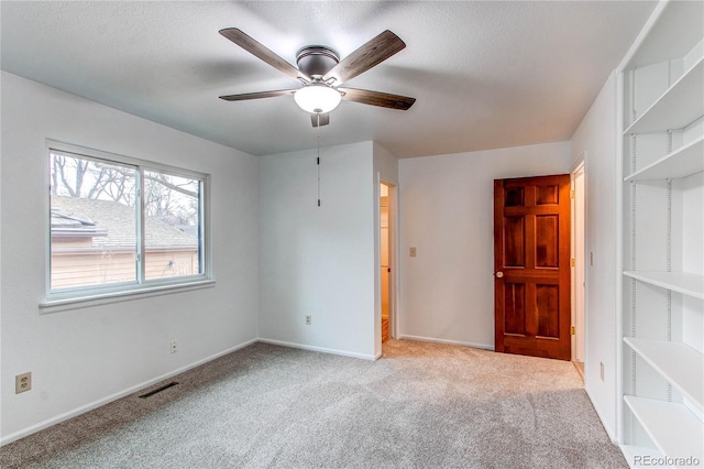 empty room featuring visible vents, baseboards, a ceiling fan, carpet, and a textured ceiling