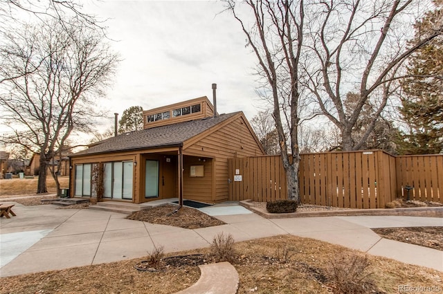 view of front of house featuring a shingled roof and fence