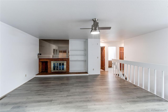 53 S Eagle Cir, Aurora, CO 80012 - unfurnished living room with a ceiling fan, a brick fireplace, and light wood-style flooring