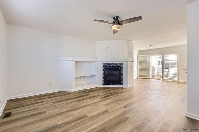 112 W Sterne Pkwy, Littleton, CO 80120 - unfurnished living room featuring baseboards, wood finished floors, a ceiling fan, and a tiled fireplace