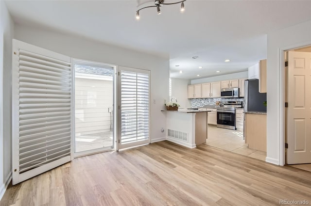 112 W Sterne Pkwy, Littleton, CO 80120 - kitchen with stainless steel appliances, light wood-type flooring, decorative backsplash, a peninsula, and baseboards