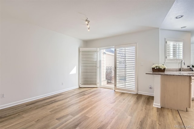 112 W Sterne Pkwy, Littleton, CO 80120 - unfurnished dining area with baseboards, light wood-style floors, and a sink
