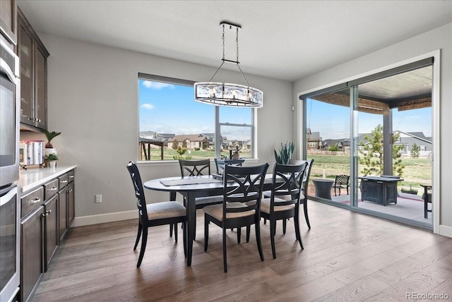 dining area with light wood finished floors, a notable chandelier, and baseboards