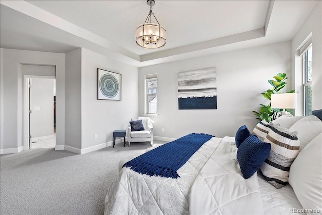bedroom with carpet flooring, baseboards, a raised ceiling, and a notable chandelier