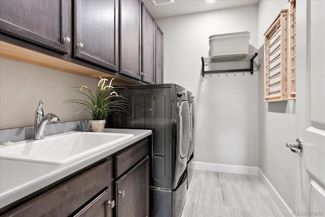 laundry area featuring baseboards, a sink, independent washer and dryer, and cabinet space