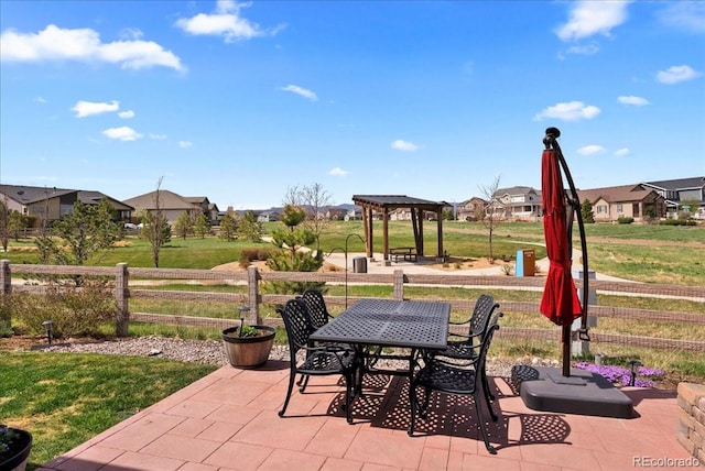 view of patio with a gazebo, fence, outdoor dining space, and a residential view