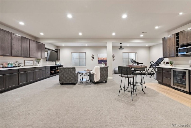 interior space featuring wine cooler, recessed lighting, dark brown cabinets, open shelves, and light countertops