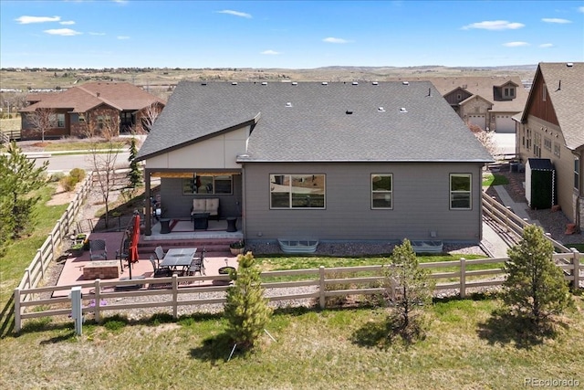 rear view of property featuring a fenced backyard, roof with shingles, a patio, and a residential view
