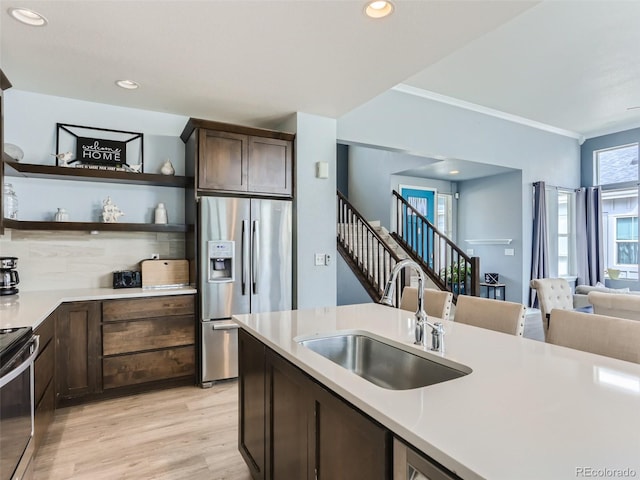 4628 Mt Shavano St, Brighton, CO 80601 - kitchen with appliances with stainless steel finishes, light countertops, dark brown cabinetry, light wood-type flooring, and crown molding