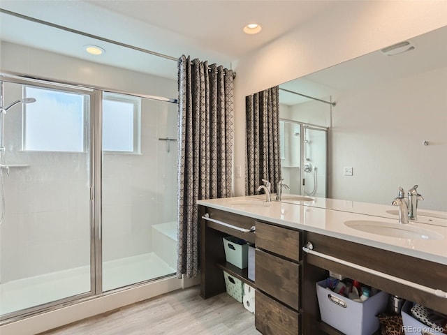 4628 Mt Shavano St, Brighton, CO 80601 - bathroom with a shower stall, double vanity, wood finished floors, and recessed lighting