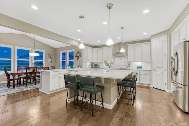 6470 Amur Ct, Castle Rock, CO 80108 - kitchen with freestanding refrigerator, wall chimney exhaust hood, lofted ceiling, a center island, and backsplash