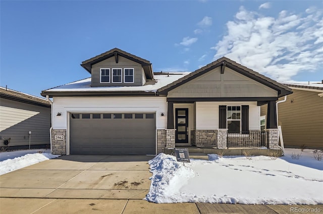 craftsman-style house with a garage, driveway, a porch, and stone siding