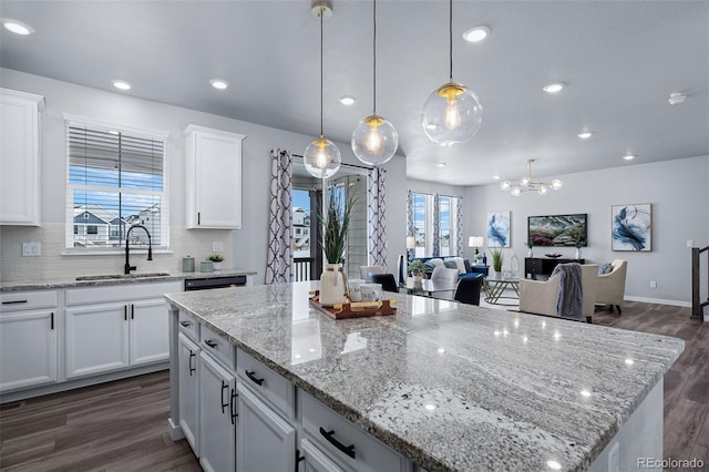 kitchen featuring tasteful backsplash, sink, decorative light fixtures, white cabinets, and a center island