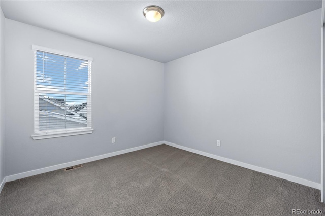 unfurnished room featuring visible vents, baseboards, and dark colored carpet