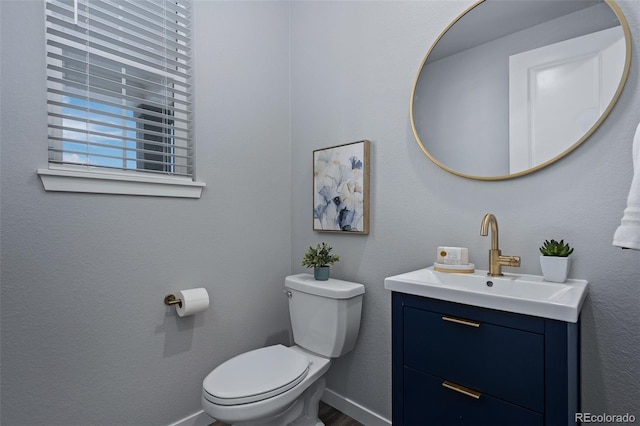 bathroom with vanity, toilet, wood finished floors, and baseboards