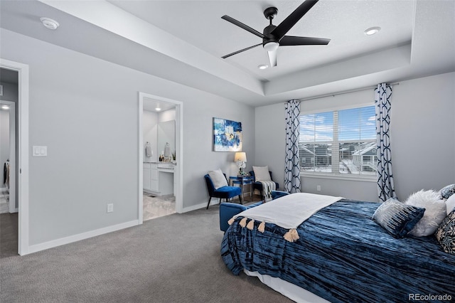 bedroom with ceiling fan, baseboards, carpet, a tray ceiling, and ensuite bathroom