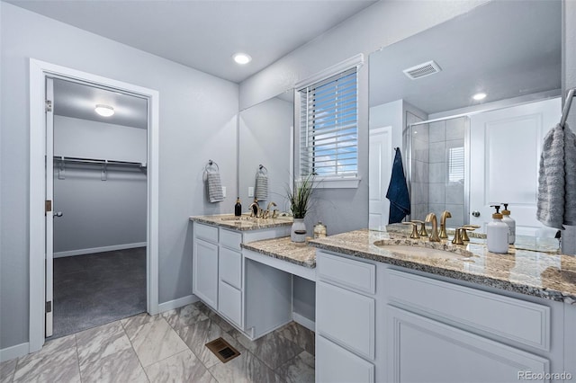 bathroom featuring vanity, visible vents, baseboards, a stall shower, and a walk in closet