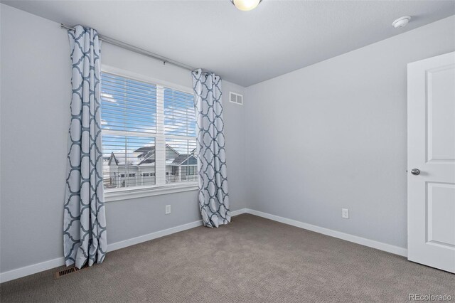 carpeted empty room featuring baseboards and visible vents