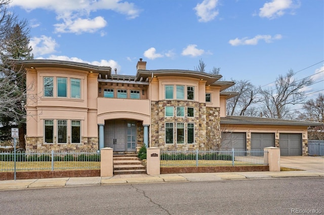 prairie-style house with stone siding, a fenced front yard, an attached garage, and stucco siding