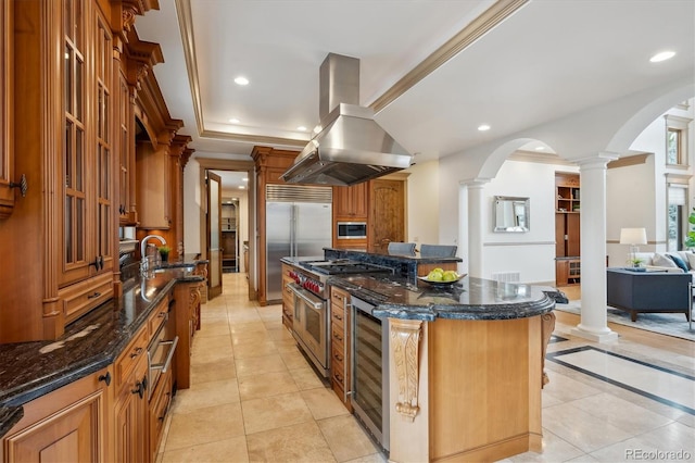 kitchen with ornate columns, built in appliances, recessed lighting, and island range hood