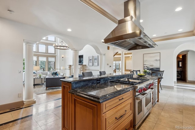 kitchen featuring island range hood, open floor plan, double oven range, brown cabinetry, and decorative columns