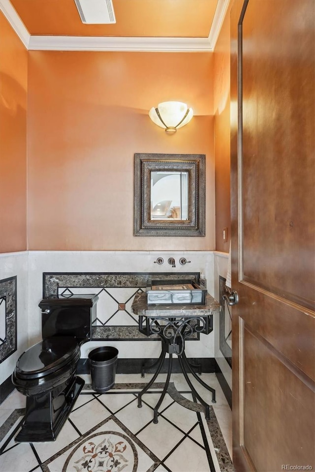 bathroom with a wainscoted wall, crown molding, visible vents, and toilet