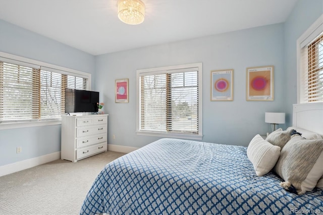 bedroom featuring light carpet, multiple windows, and baseboards