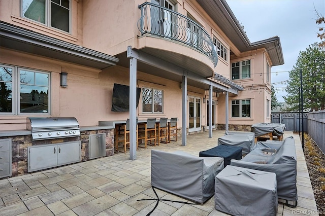 view of patio featuring area for grilling, a balcony, a fenced backyard, outdoor dry bar, and grilling area