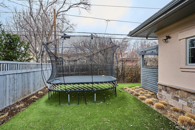 view of yard with a trampoline and a fenced backyard