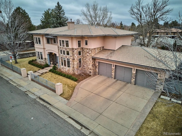 prairie-style home with a fenced front yard, a garage, stone siding, stucco siding, and a chimney