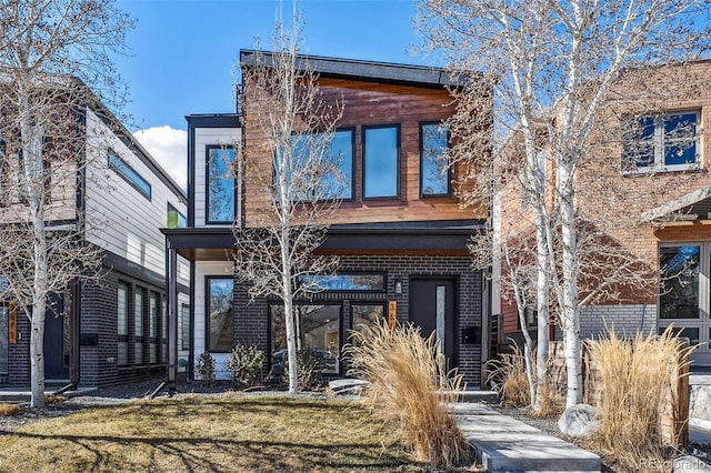 back of house featuring a lawn and brick siding