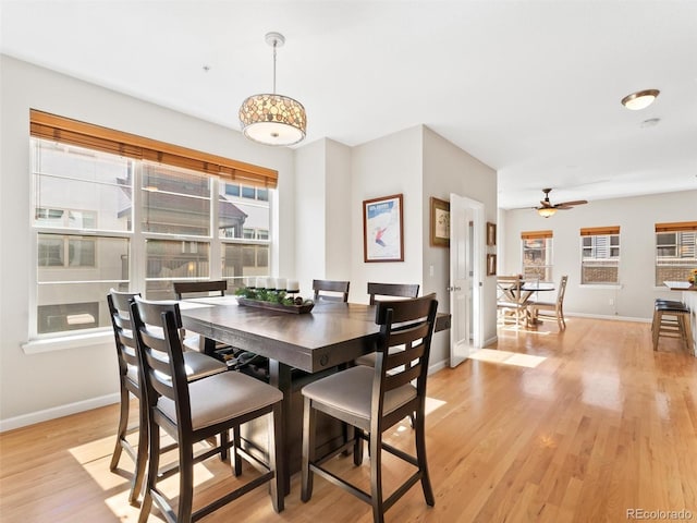 dining space with light wood-type flooring, ceiling fan, and baseboards