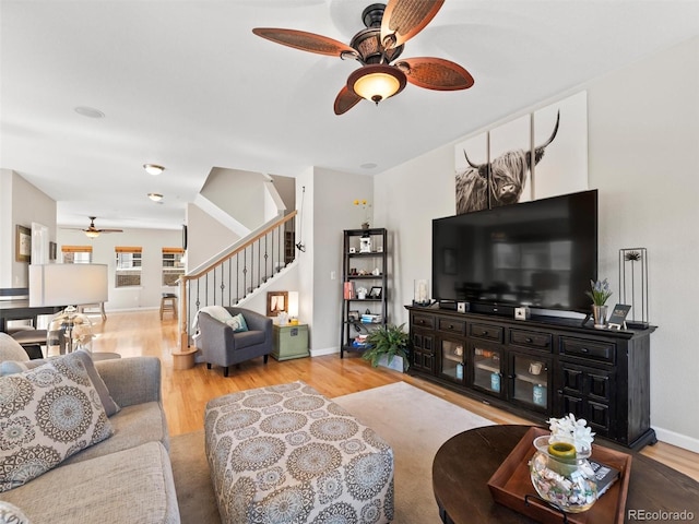 living room featuring stairs, wood finished floors, a ceiling fan, and baseboards