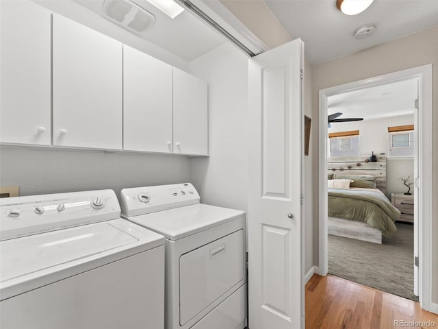 laundry area with cabinet space, washer and clothes dryer, and light wood finished floors