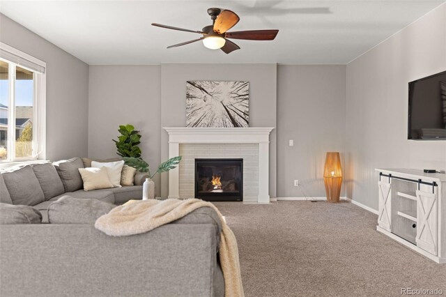 living room featuring carpet floors, ceiling fan, and a tiled fireplace