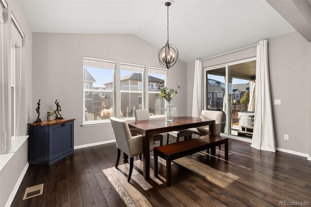 dining area with a notable chandelier, dark hardwood / wood-style floors, and vaulted ceiling