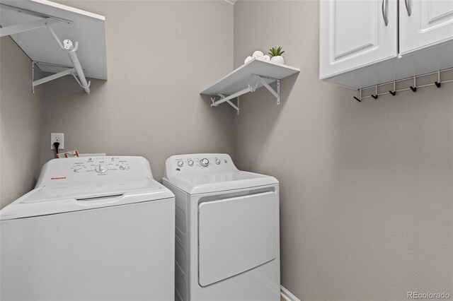 clothes washing area with cabinets and washing machine and clothes dryer