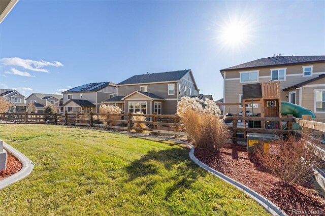 rear view of property featuring a playground and a yard