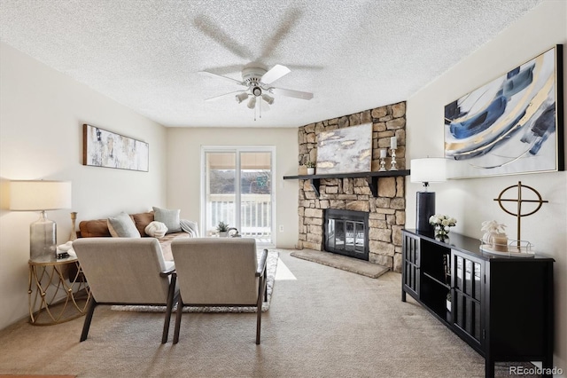 carpeted living room with ceiling fan, a stone fireplace, and a textured ceiling