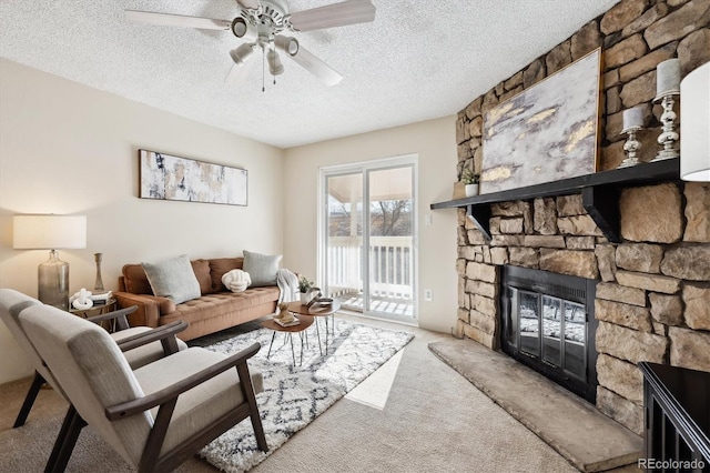 living room featuring ceiling fan, a fireplace, carpet floors, and a textured ceiling