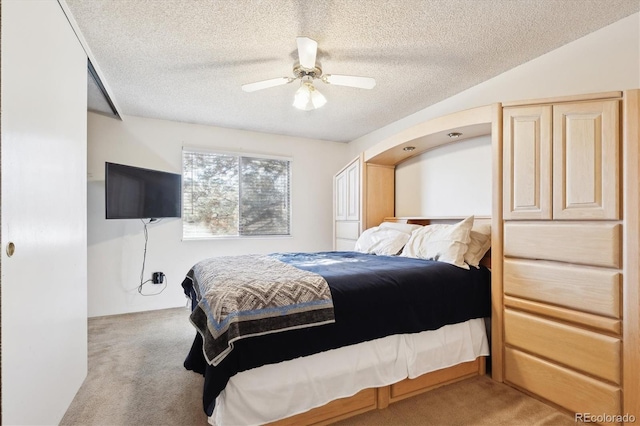 bedroom featuring a textured ceiling, ceiling fan, and light carpet