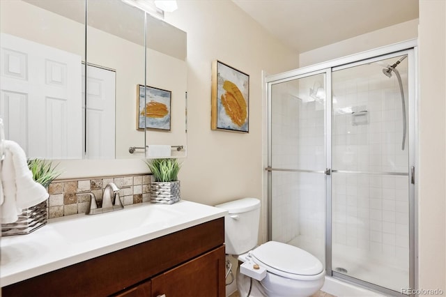 bathroom with vanity, toilet, a shower with shower door, and backsplash