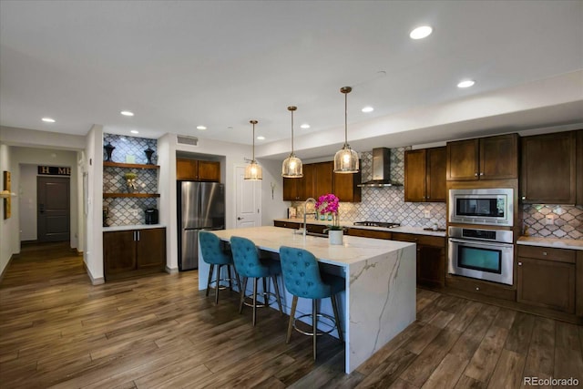 kitchen featuring dark wood-style flooring, visible vents, wall chimney exhaust hood, backsplash, and stainless steel appliances